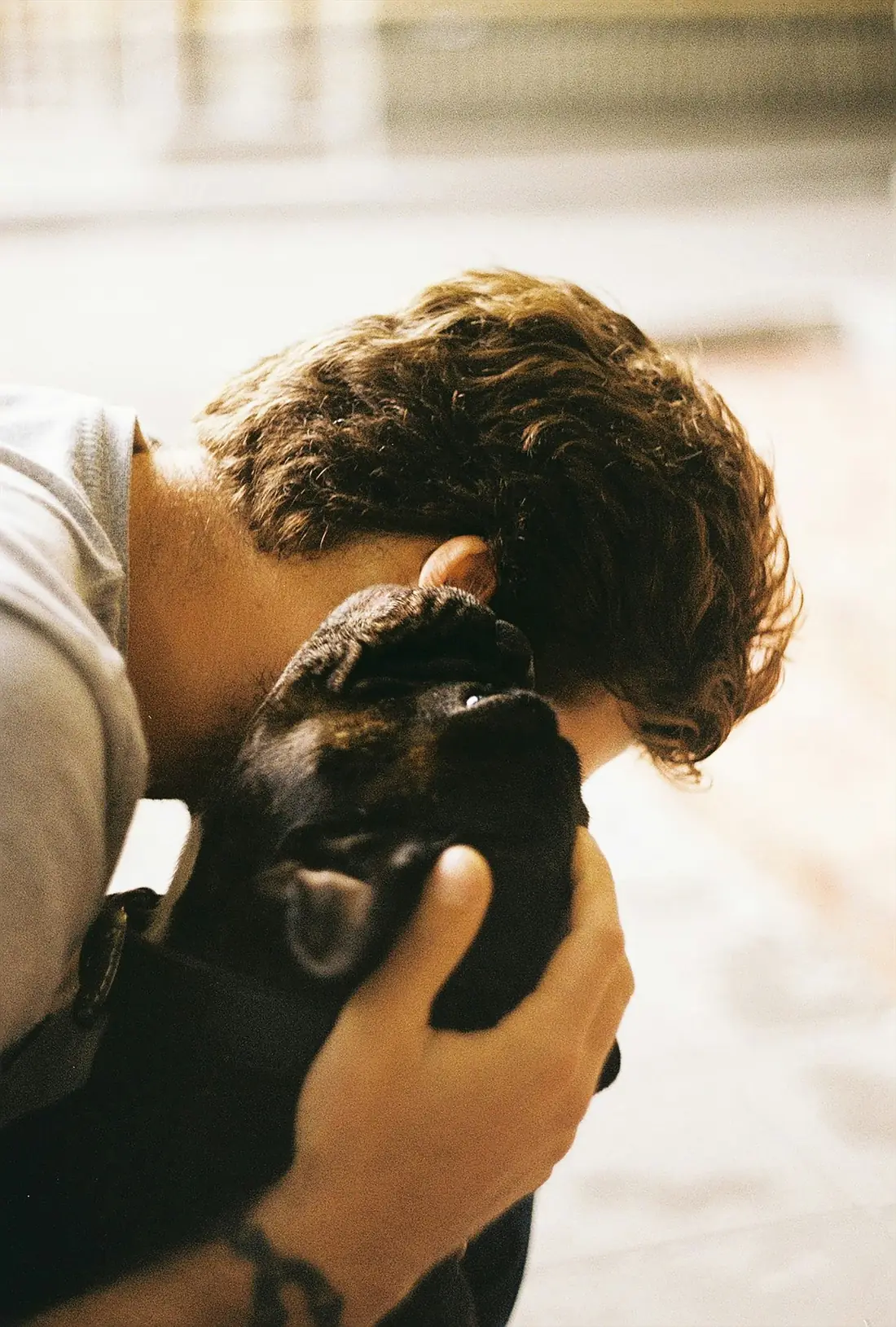 Homem a beijar um cachorro preto que segura nas mãos